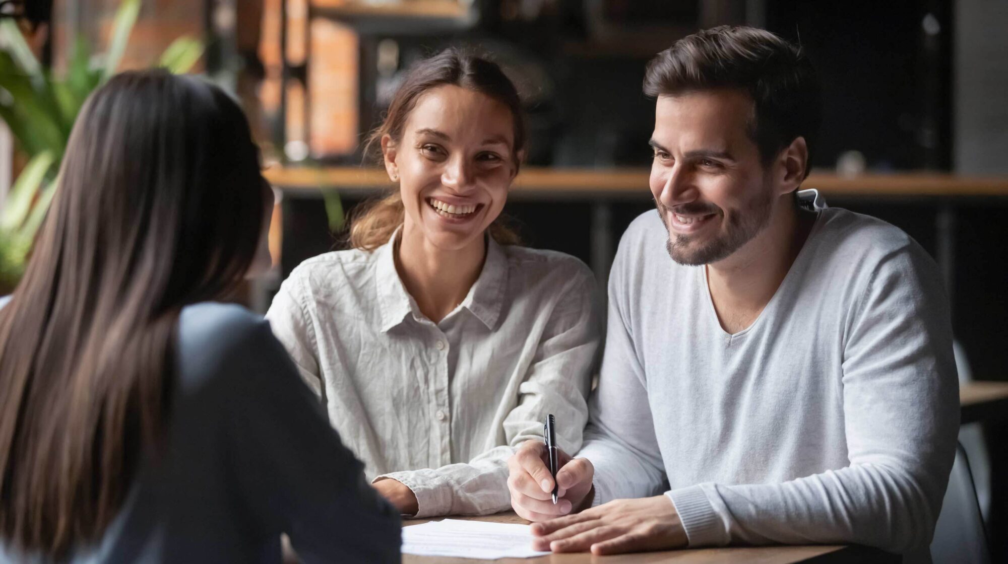 Happy couple filling out paperwork with an agent